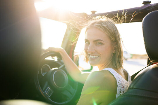 Young Caucasian woman smiles while driving on a road trip