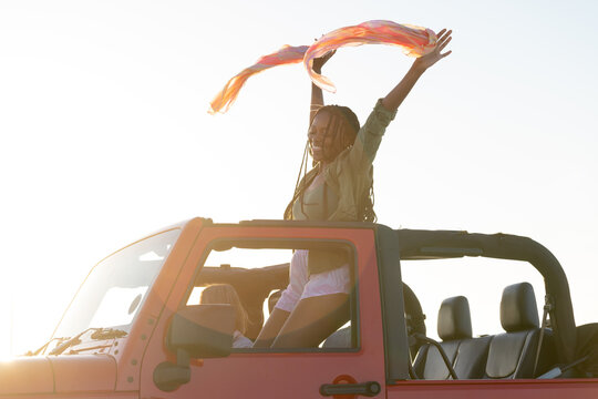 Young African American woman enjoys a vibrant sunset from a vehicle on a road trip