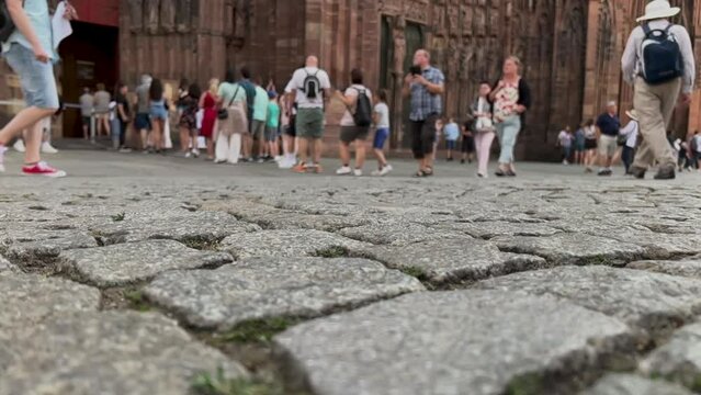 Slow motion views of tourists lining up to enter the Strasbourg Cathedral Notre Dame in Strasbourg, France. Charming cobblestone streets in the foreground of view.
