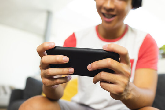 Teenage Asian boy plays a game on his smartphone, with copy space