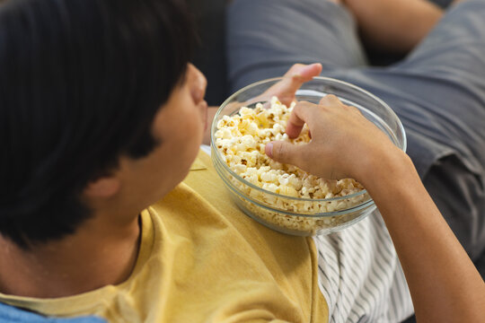 Teenage Asian boy enjoys a bowl of popcorn at home