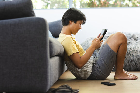 Teenage Asian boy relaxes at home with a smartphone