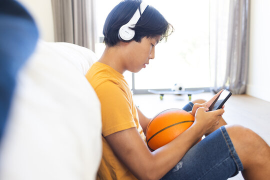 Teenage Asian boy enjoys music on his headphones at home, with copy space