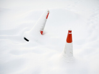 Red traffic safety cones covered in snow