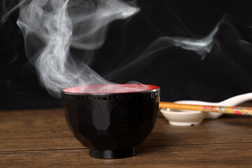 Smoke vape fog rising flowing out of miso soup black red white bowl on dark black background - 736742587