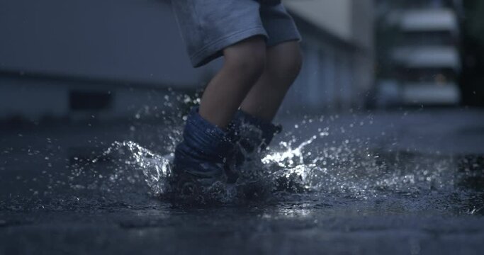 Child in rain boots leaping joyfully in puddle with ultra slow-motion capture, nostalgic childhood concept
