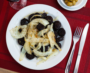 Spanish blood sausage morcilla served with grilled onion on plate