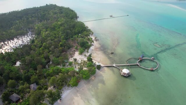 Aerial Descending Towards Leebong Island's Over Water Bungalows Resort with Long Wooden Piers Over Emerald Sea in Belitung Indonesia