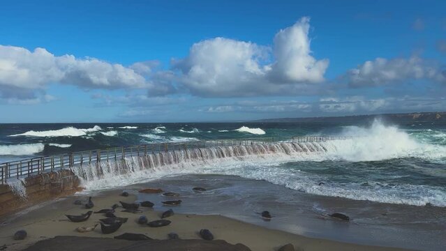 Ocean waves crashing and smashing over La Jolla Childrens Pool during King Tide with ruff water.