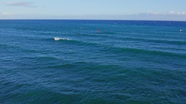 Drone footage of a small group of kite boarders sailing across the oceans surface near Diamond Head Oahu Hawaii