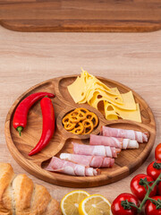 Wooden platter with assorted cheeses, sausages and vegetables. Cheese plate, snacks for the holiday table.