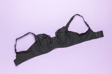 An unbuttoned female black bra on a purple background.
