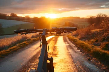 Poster Early morning ride captured through the handlebars of a bicycle, with a frosted landscape illuminated by the sunrise © LifeMedia