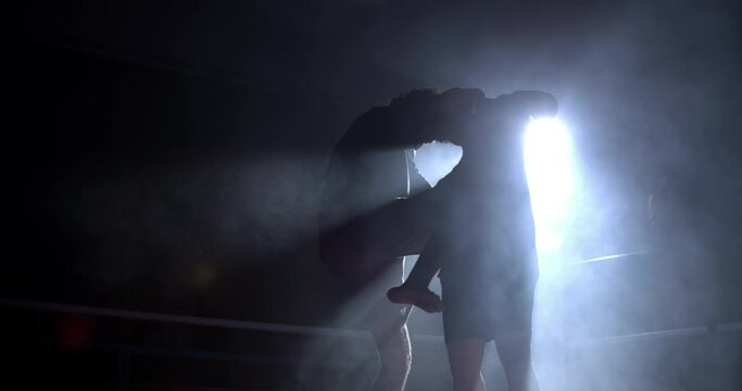 Muay Thai fighters battling each other inside boxing ring clinching each other while attempting to knee kick opponent