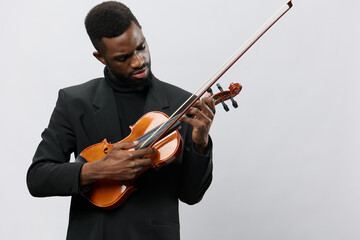 A talented African American man in black suit playing violin against a clean white background