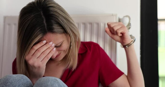 Stressed blonde woman handcuffed to radiator in captivity