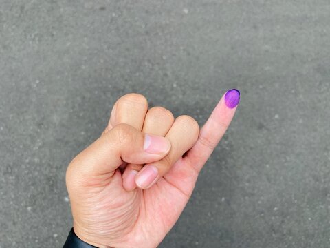 Indonesian man showing little finger covered with ink after giving vote on election or Pemilu