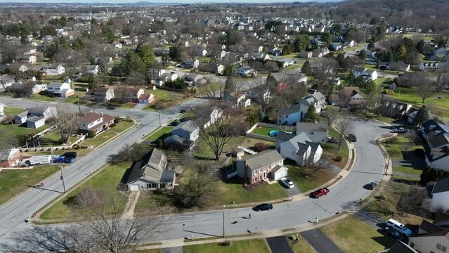 American housing and residential area in little town of USA. Parking cars and leafless trees during sunny day in winter. Aerial tilt up panorama.