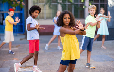 Fototapeta premium Positive african-american girl performing street dance with her friends outdoors.