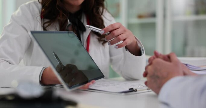 Doctor shows variants of treatment on tablet to patient