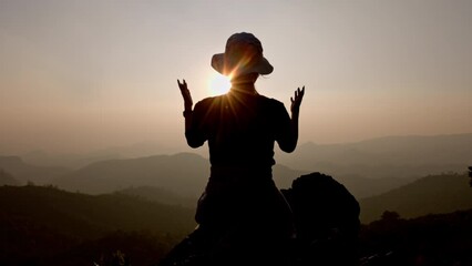 Slow motion, Silhouette of woman praying over beautiful sunrise background, beautiful landscape, pay homage, spirituality and religion, Christianity concept.
