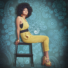 Portrait, young woman and fashion in 70s retro colour jumpsuit and sitting on chair. African trend,...