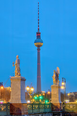 The famous Television Tower of Berlin with two white sculptures at twilight