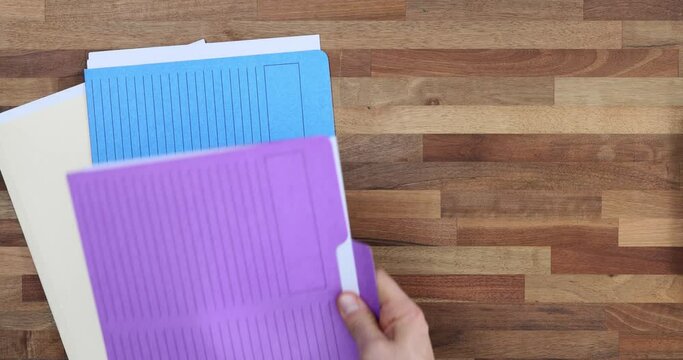 Man puts colourful folders with papers on desk in office