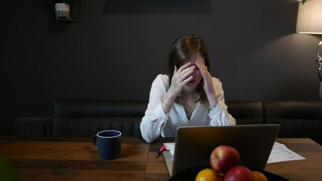Depressed woman working at home stressed with work and paperwork in front of a computer receiving bad news