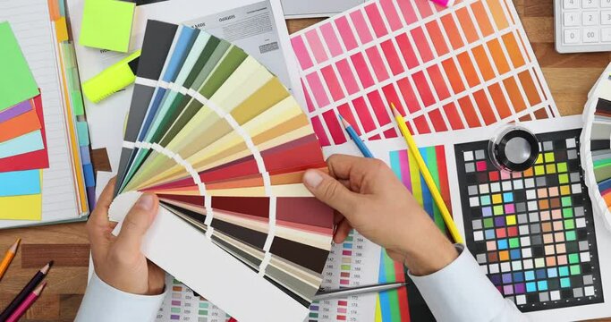 Female designer holds color swatch fan working in office