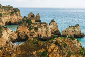 Rugged coastline adorned with natural arches and caves, where turbulent ocean waves meet the rocky shore, Algarve, Portugal