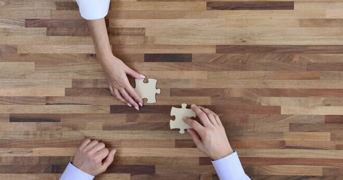 Businesspeople connect jigsaw puzzles showing teamwork at table
