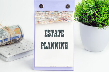 Estate Planning text writing on a desktop tear-off calendar on a white background, next to a calculator with a roll of banknotes with a flower out of focus in the background