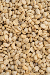 Unroasted green Arabica coffee beans flat surface. Backgrounds. Closeup macro food photo directly from above.