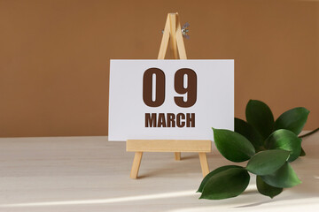 March 9th. Day 9 of month, Calendar date. Green branch, easel with the date and month on desktop....
