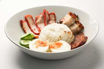 Red Pork and Crispy Pork on Rice Served with Chinese sausage, cucumber, boiled egg. and boiled bone soup, red pork and crispy pork on rice It is a popular food in Thailand.