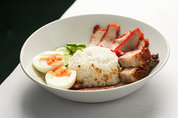 Red Pork and Crispy Pork on Rice Served with Chinese sausage, cucumber, boiled egg. and boiled bone soup, red pork and crispy pork on rice It is a popular food in Thailand.