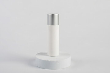 Plastic white tube for cream or lotion. Skin care or sunscreen cosmetic with stylish props on white background 