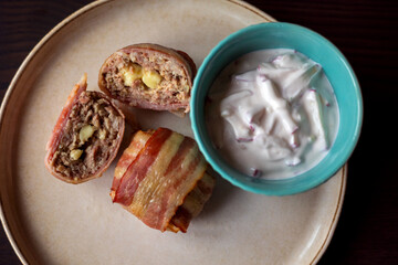 savory delight: delicious dish with meatballs wrapped in bacon, filled with mozzarella and yogurt sauce