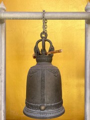 Obraz premium Old hanging bell with bright yellow wall background in temple, Knock for hope, fate, luck in Thailand