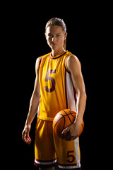 Athletic young Caucasian female basketball player poses confidently in basketball gear on a black ba - obrazy, fototapety, plakaty