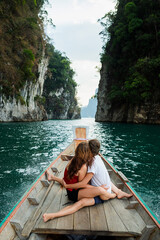 A couple of young people in love are sailing on a boat and sitting on the stern, admiring the...