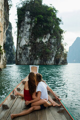 A couple of young people in love are sailing on a boat and sitting on the stern, admiring the...