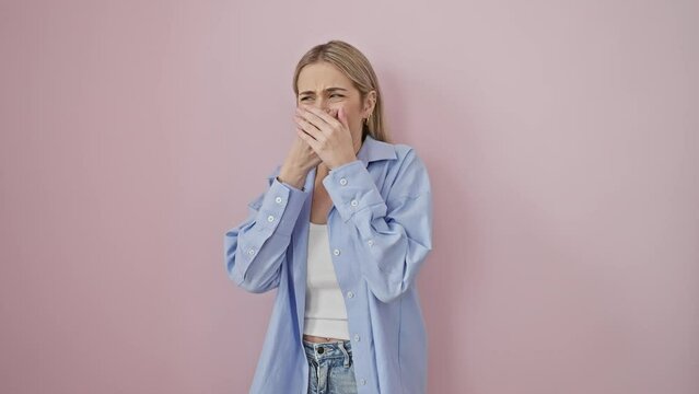 Disgusted young blonde woman holding her breath over stinky smell, wearing shirt. shocked expression of intolerable, offensive stench on isolated pink background.