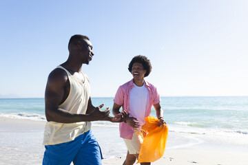 An African American couple enjoys a sunny beach day, collecting trash