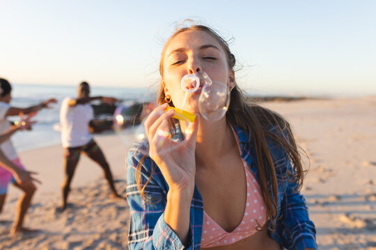 Young Caucasian woman blows bubbles on a sunny beach