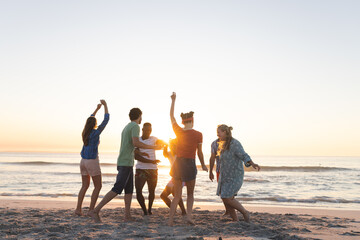 Diverse group of friends enjoy a beach sunset