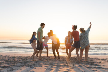 Fototapeta premium Diverse group of friends enjoy a beach outing at sunset
