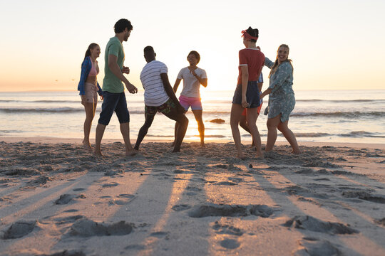 Diverse group of friends enjoy a beach outing at sunset