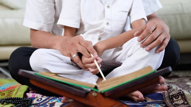 Closeup of father and son reading Islamic holy bible